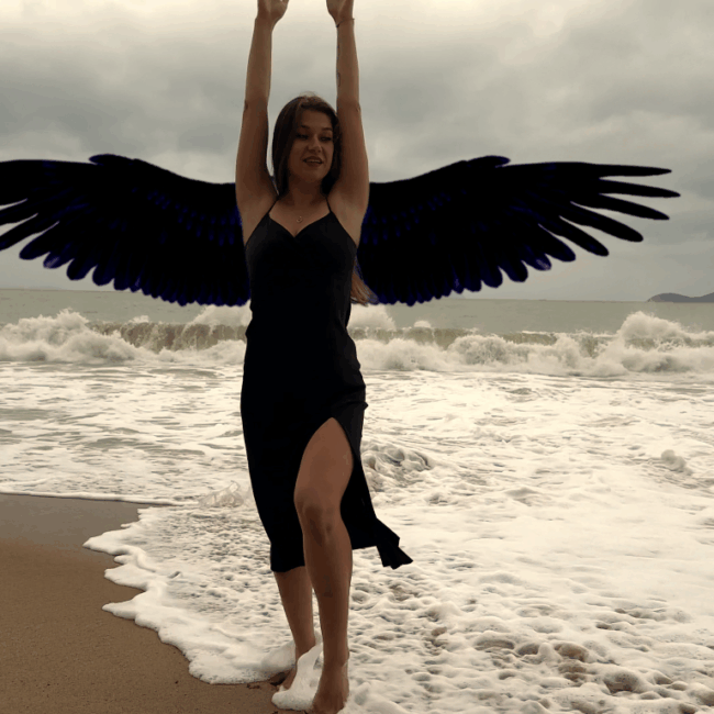 Lisa in a black dress on the beach of Nha Trang Vietnam with large black wings